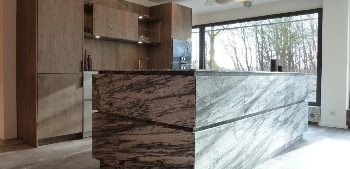 Eggersmann Programm VANCOUVER Front Echtholz Eiche silberbraun furniert und gebürstet. 
Arbeitsplatte Edelstahl massiv gebürstet 5 mm, Spülbecken eingeschweißt.
Insel: Front und Platte UNIQUE E Pietra Viva honed, Marmor Oberfläche gesandstrahlt und mit Diamantbürste gebürstet